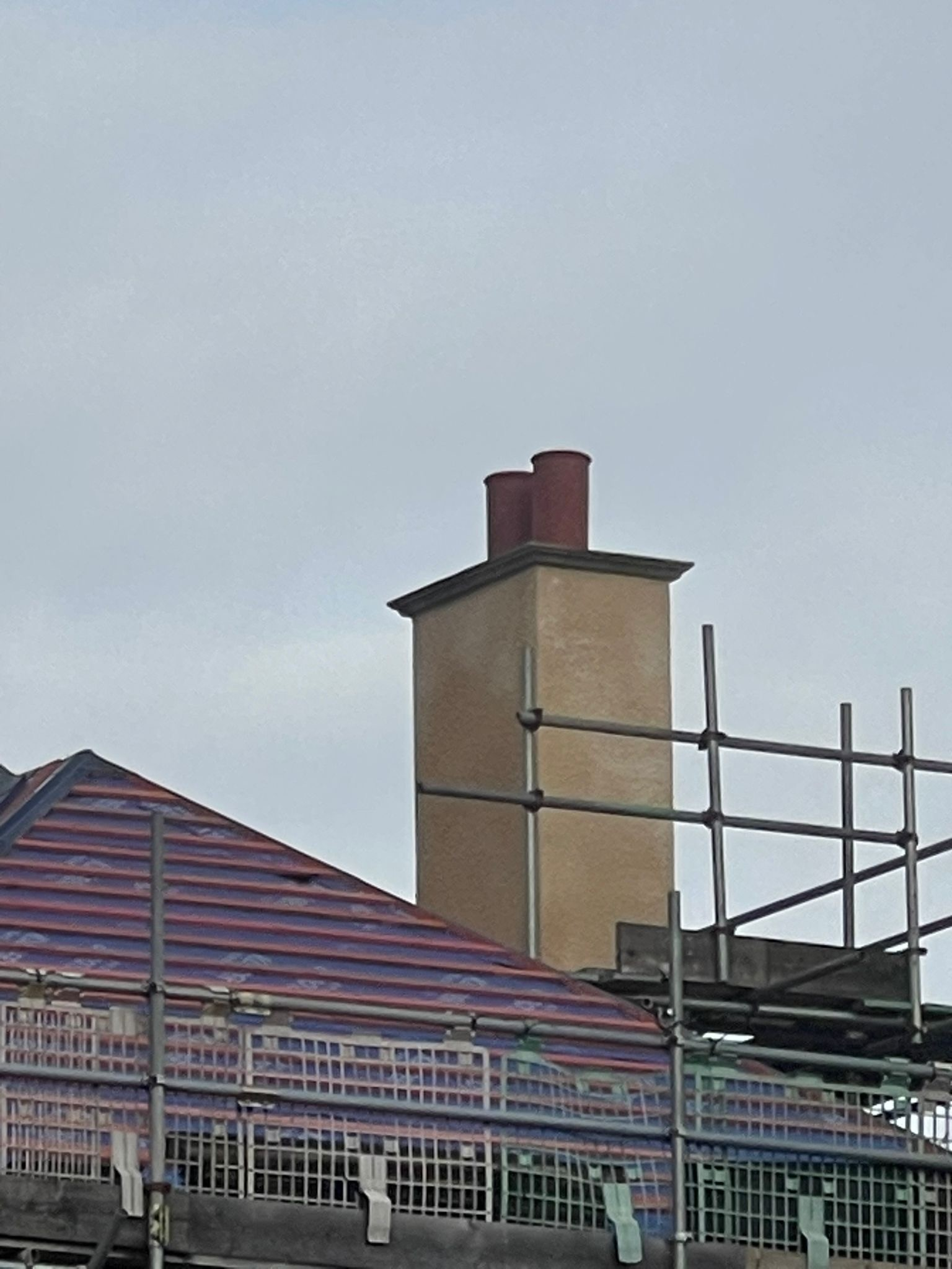 The rebuilt chimney at Coed Parc rising against the sky, a visible sign of the restoration work returning the building to its original character
